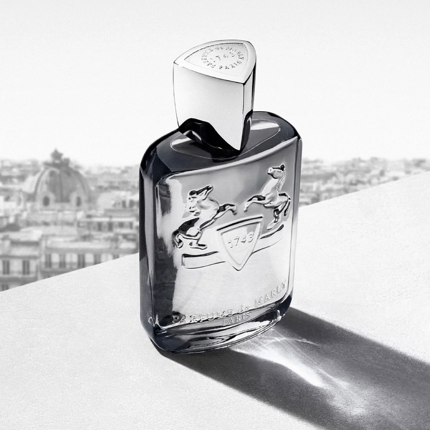 Perfume bottle with brand logo on a light surface with blurred background