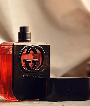 Gucci perfume bottle with red liquid on a beige background