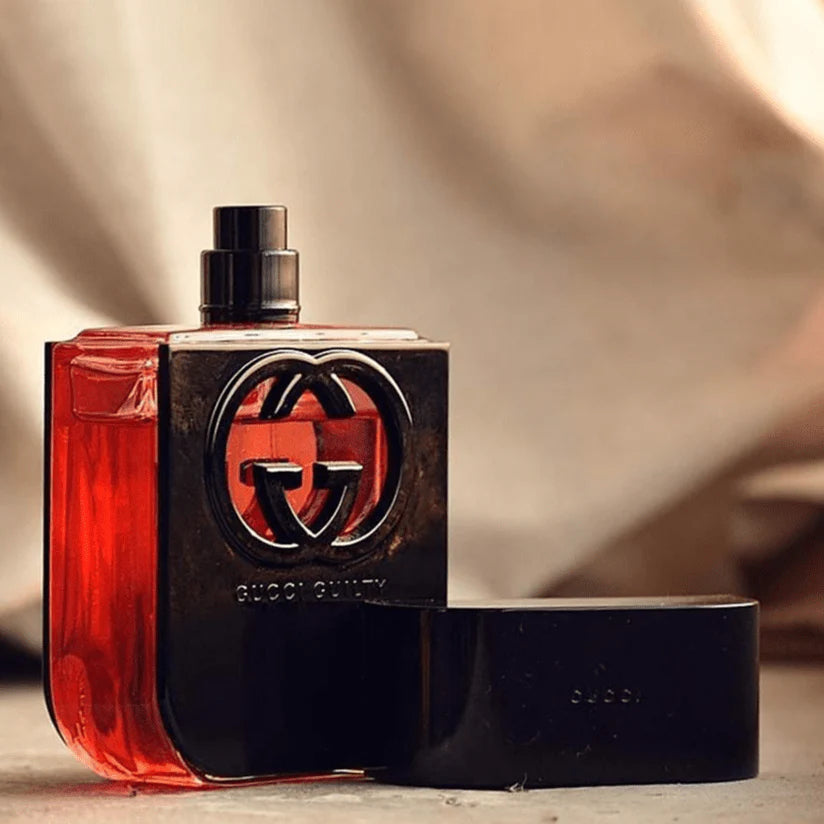 Gucci perfume bottle with red liquid on a beige background