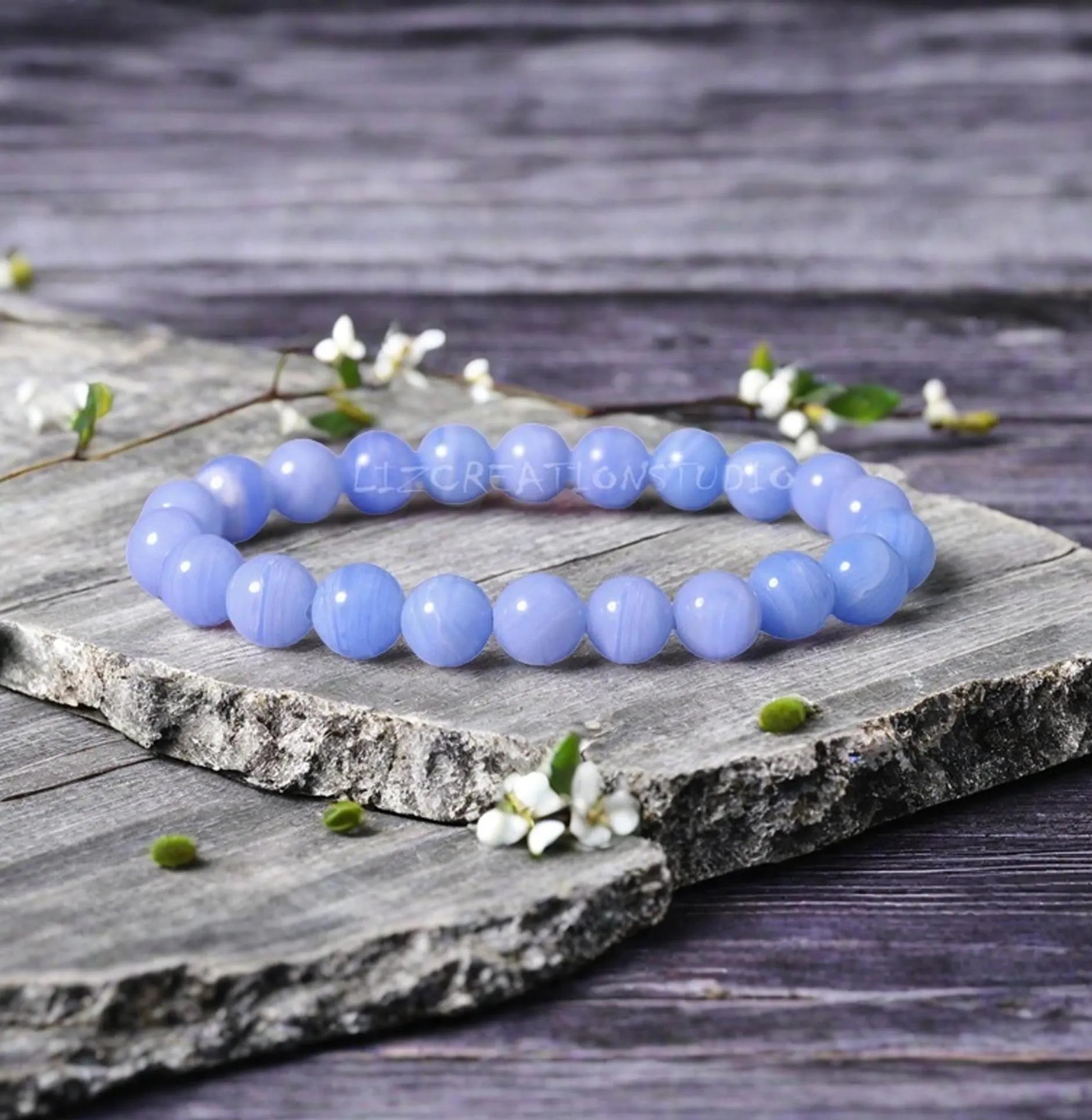 Blue beaded bracelet on a wooden surface with flowers