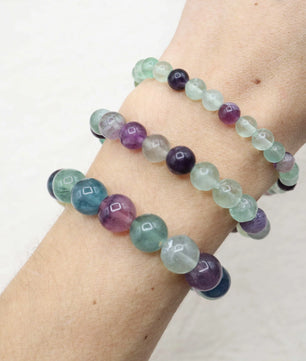 Multicolored beaded bracelet on a wrist against a white background