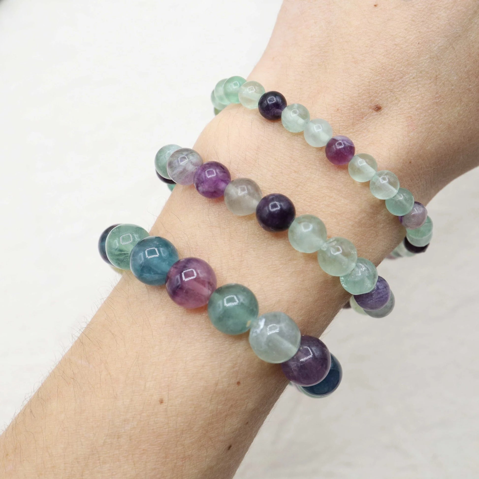 Multicolored beaded bracelet on a wrist against a white background