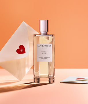 Perfume bottle labeled 'Lovenotes' with a heart-shaped card on an orange background