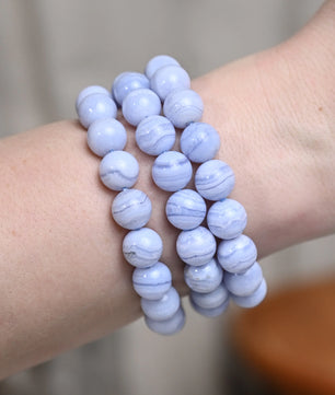 Three blue beaded bracelets on a wrist with a neutral background