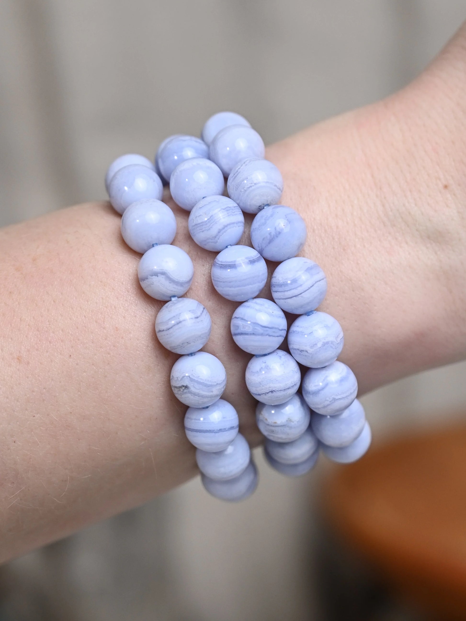 Three blue beaded bracelets on a wrist with a neutral background