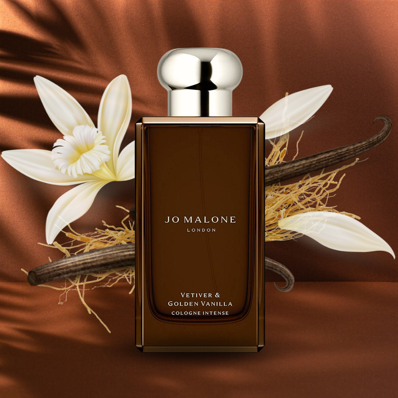 Jo Malone Vetiver & Golden Vanilla cologne bottle with vanilla flowers and pod on a brown background