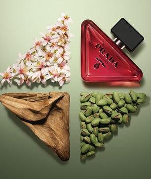 Prada perfume bottle with flowers, wooden leaf, and green seeds on a green background