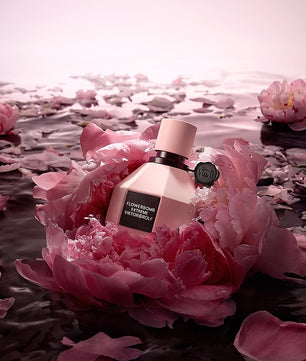 Perfume bottle on a pink flower with water and petals in the background