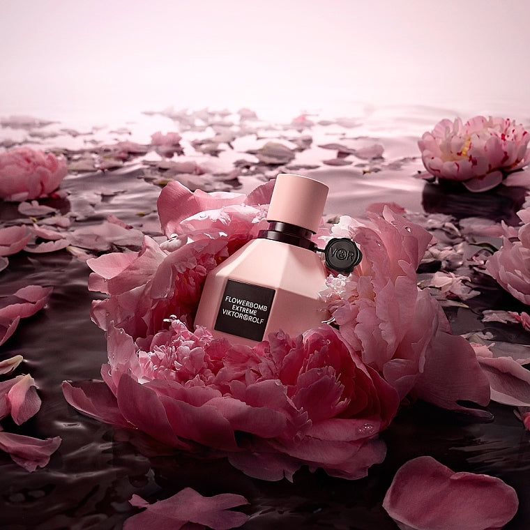 Perfume bottle on a pink flower with water and petals in the background
