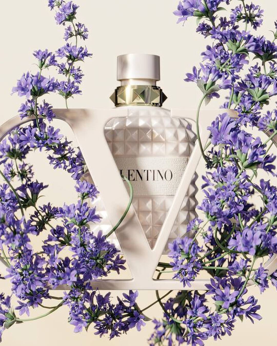 Fragrance bottle with geometric design surrounded by purple flowers on a light background