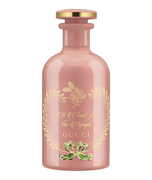A pink GUCCI Eau De Parfum bottle with a gold cap and floral design around the label.
